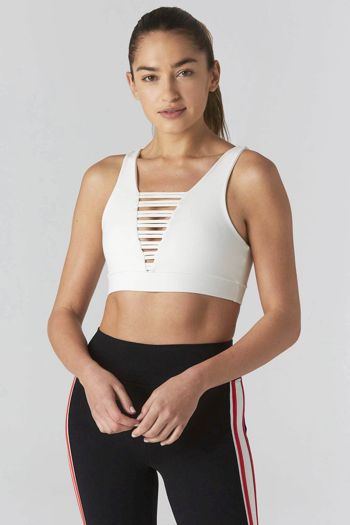Woman is wearing 925 fit cream sports bra and black yoga pants