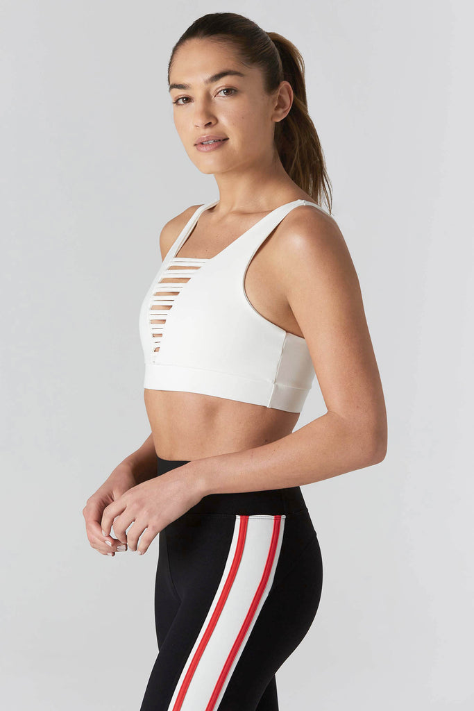 Woman is wearing 925 fit cream sports bra and black yoga pants