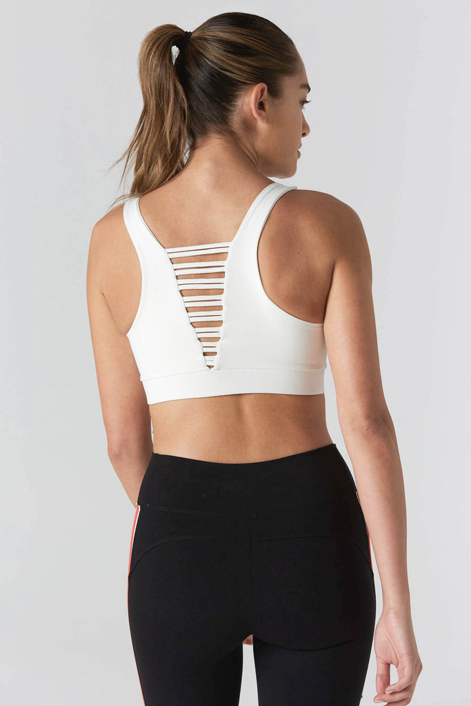 Woman is wearing 925 fit cream sports bra and black yoga pants