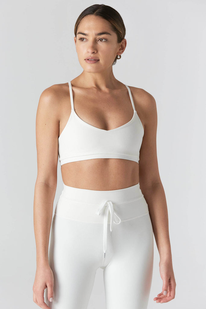 Woman is wearing a 925 Fit Cream In House Racerback Sports Bra. Front view.