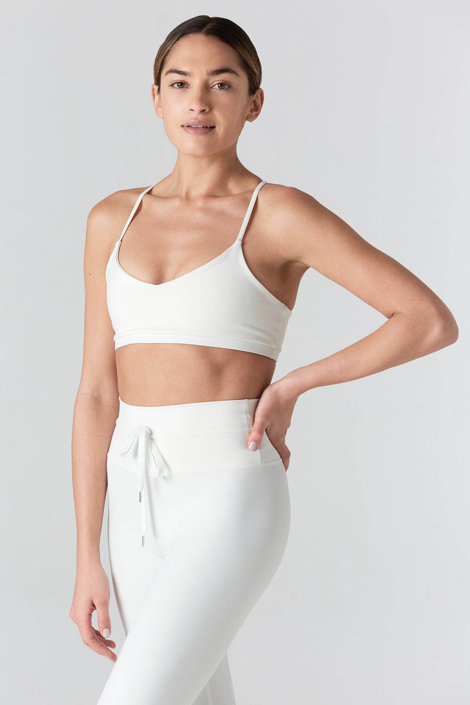 Woman is wearing a 925 Fit Cream In House Racerback Sports Bra. Front side view.