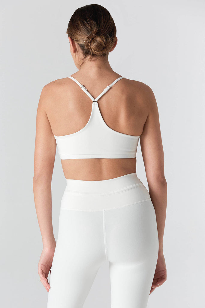 Woman is wearing a 925 Fit Cream In House Racerback Sports Bra. Back view.