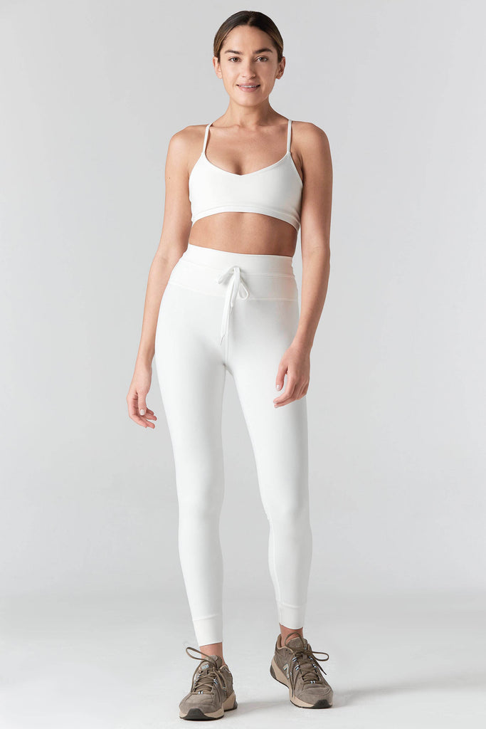 Woman is wearing a 925 Fit Cream In House Racerback Sports Bra. Full Front view with 925 Fit cream pants.