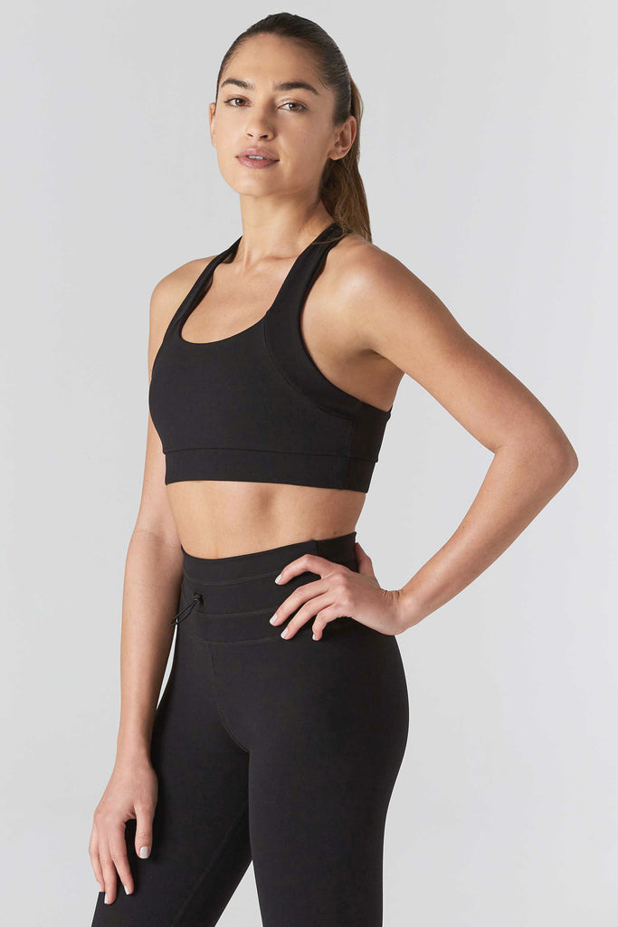 Woman wearing black 9two5fit multi task racerback sports bra. Front to side view.