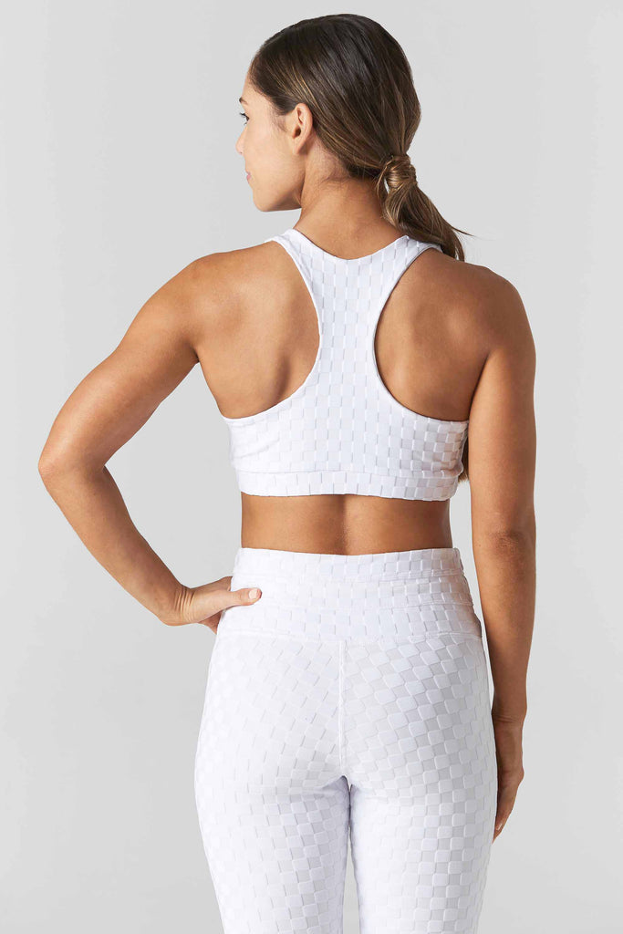 Woman is wearing a 925 Fit White Spot Light Jacquard Sports Bra. Back view.