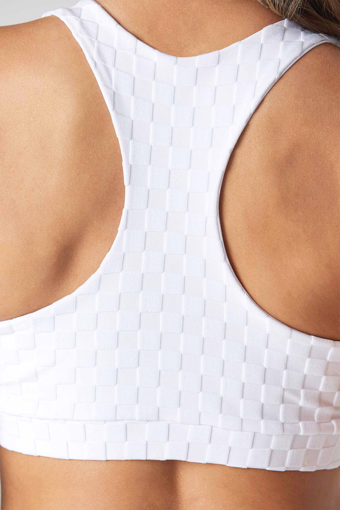 Woman is wearing a 925 Fit White Spot Light Jacquard Sports Bra. Close up backview.