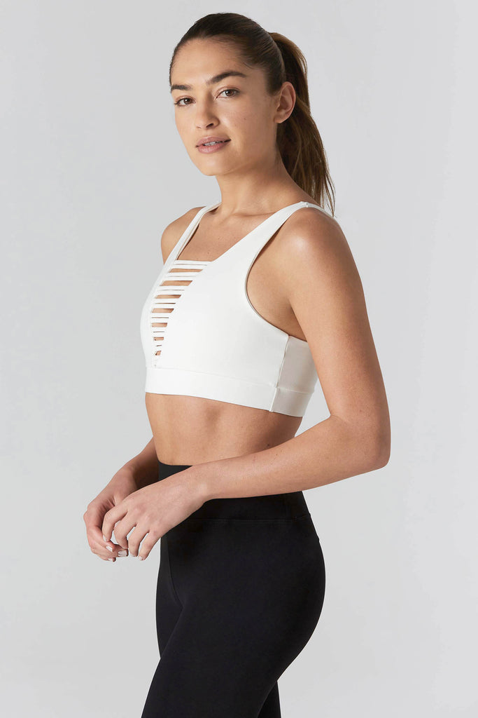 Woman is wearing 925 fit cream sports bra and black yoga pants